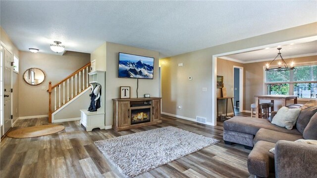 living room with dark hardwood / wood-style floors, an inviting chandelier, and ornamental molding