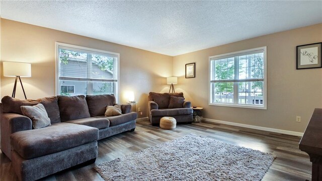 living room featuring a textured ceiling, dark wood-style floors, and baseboards