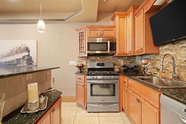 kitchen featuring backsplash, stainless steel appliances, sink, light tile patterned flooring, and dark stone countertops