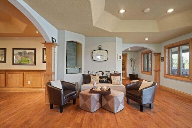 living room featuring a tray ceiling, light hardwood / wood-style floors, and a textured ceiling