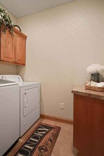 clothes washing area with cabinets, separate washer and dryer, and light tile patterned floors