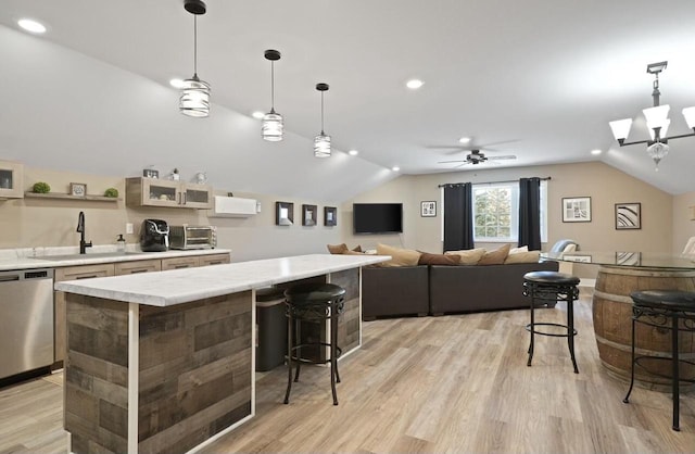 kitchen featuring light wood-type flooring, hanging light fixtures, dishwasher, and a breakfast bar area