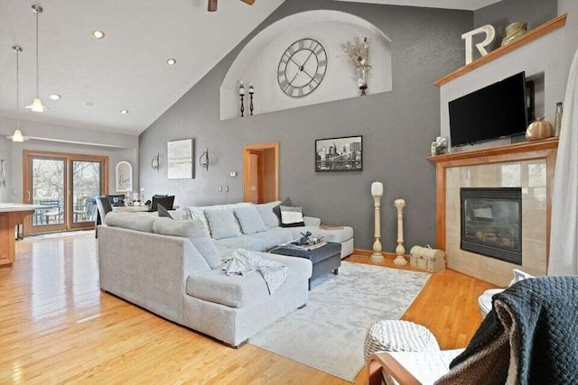 living room with a fireplace, high vaulted ceiling, and light hardwood / wood-style floors