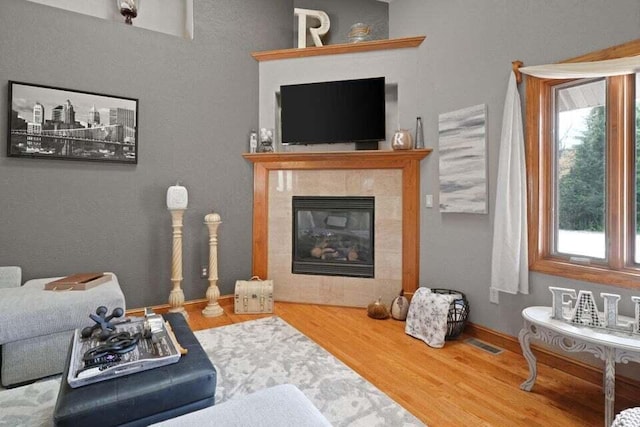 living room with wood-type flooring, plenty of natural light, and a tile fireplace