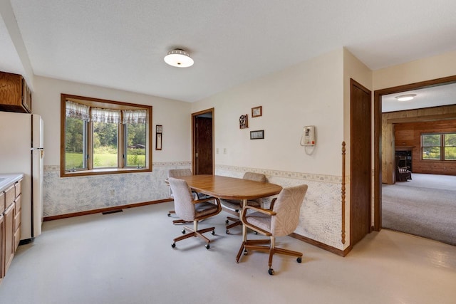 dining area featuring visible vents, wooden walls, wallpapered walls, a wainscoted wall, and light colored carpet