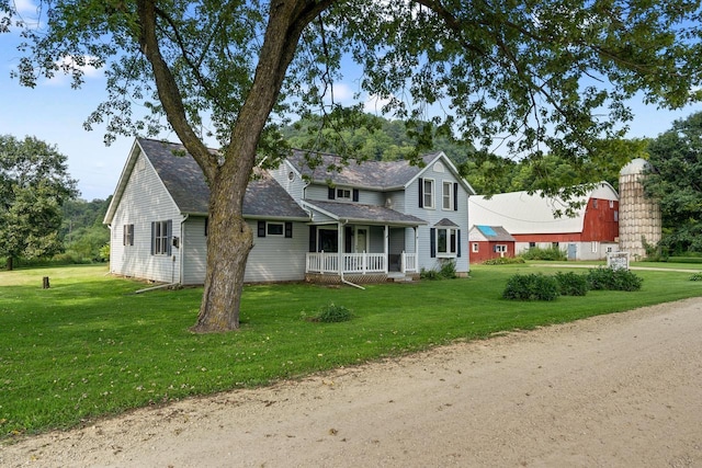 view of front of house with a front yard, covered porch, and roof with shingles