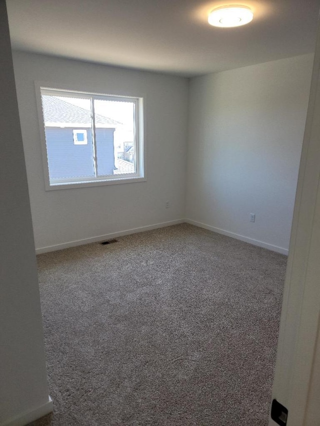 empty room featuring carpet floors, visible vents, and baseboards