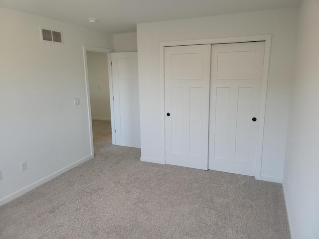 unfurnished bedroom with baseboards, visible vents, a closet, and light colored carpet