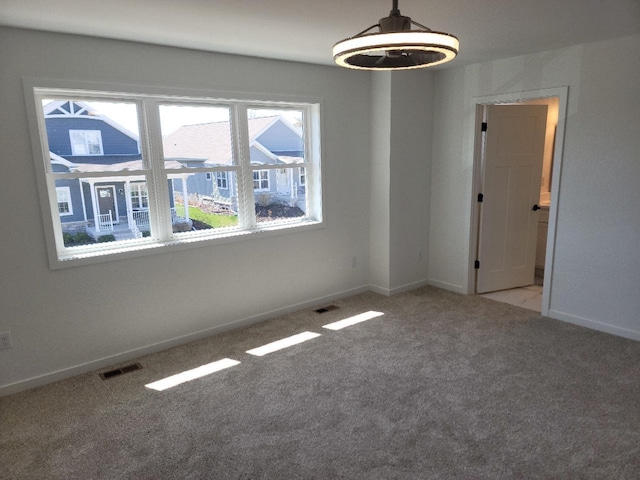 carpeted spare room with visible vents and baseboards