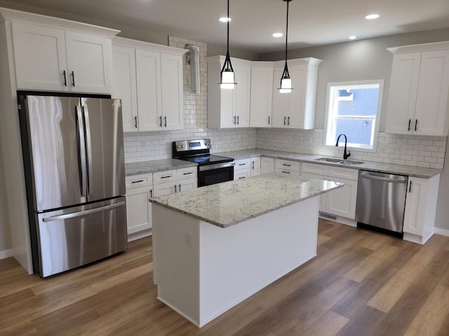 kitchen featuring a center island, pendant lighting, appliances with stainless steel finishes, white cabinetry, and a sink