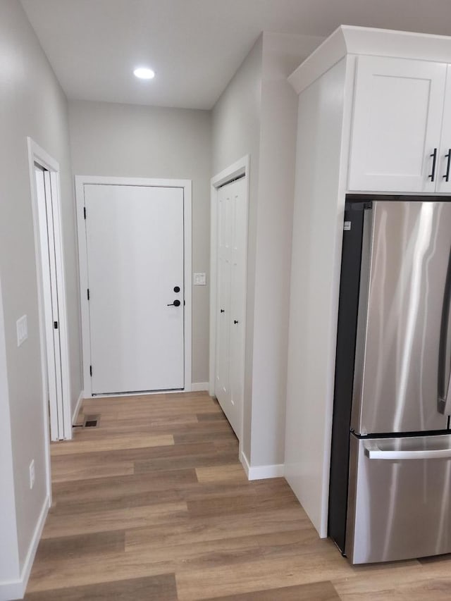 hall featuring recessed lighting, visible vents, light wood-style flooring, and baseboards