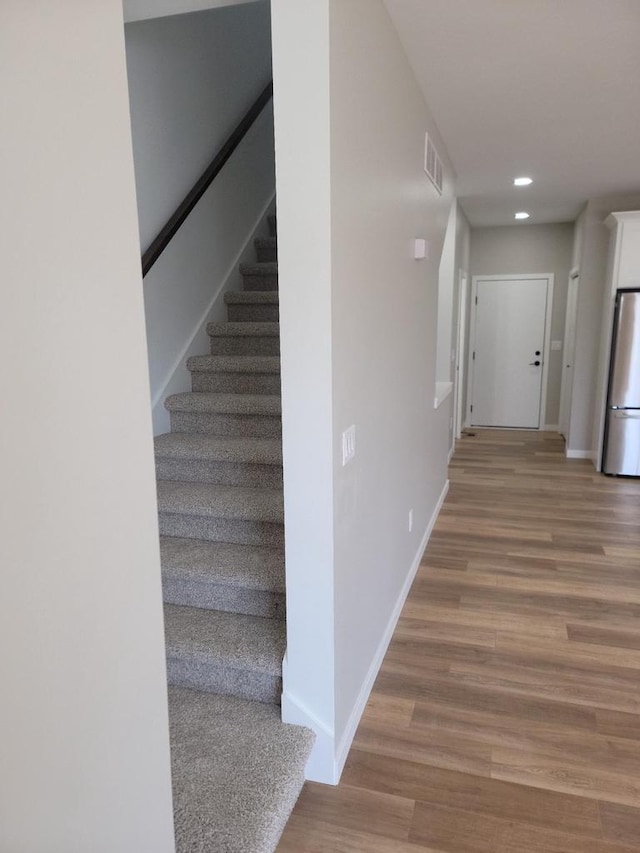 corridor with recessed lighting, wood finished floors, visible vents, baseboards, and stairway