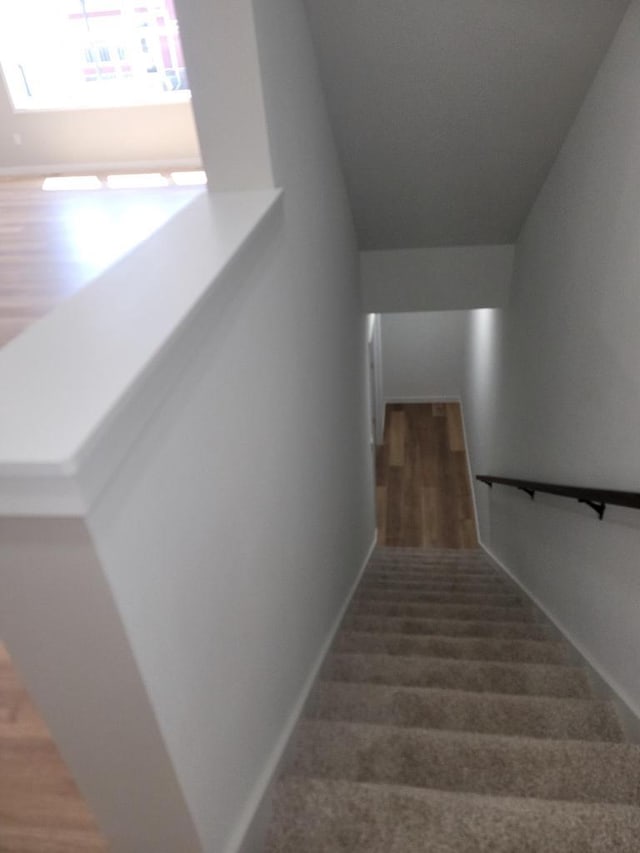 staircase featuring wood finished floors and baseboards