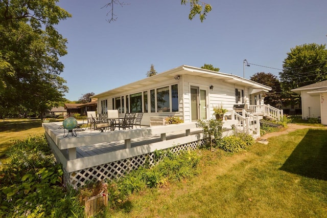 rear view of house with a deck and a lawn