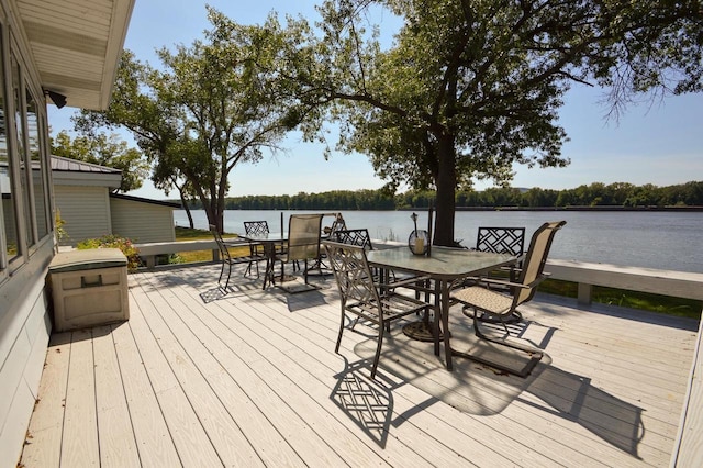 wooden terrace featuring outdoor dining space and a water view