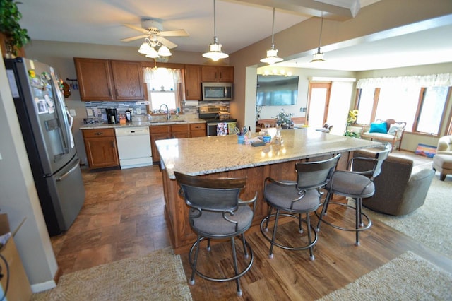 kitchen with a sink, appliances with stainless steel finishes, backsplash, and brown cabinets