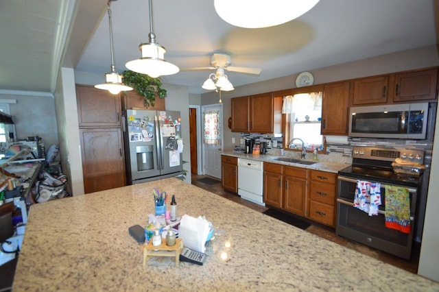 kitchen featuring a sink, appliances with stainless steel finishes, backsplash, brown cabinets, and pendant lighting