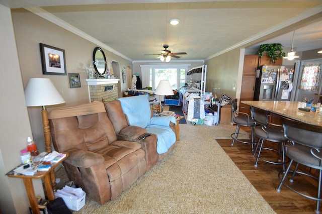 living area with a ceiling fan, ornamental molding, and dark wood-style flooring