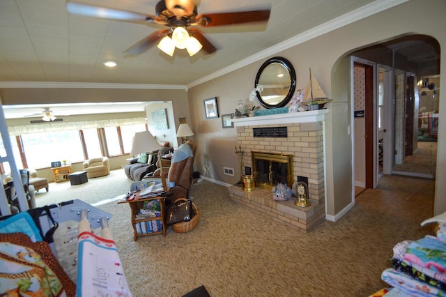 carpeted living room with arched walkways, visible vents, ornamental molding, a brick fireplace, and ceiling fan