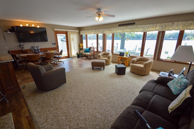 living room featuring a ceiling fan and a water view