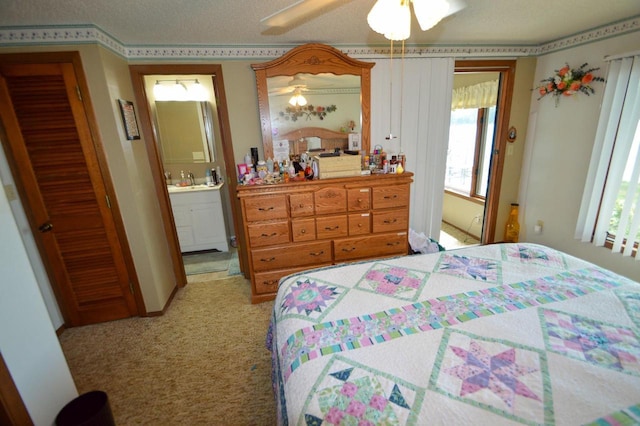 bedroom featuring light carpet, a textured ceiling, a ceiling fan, and connected bathroom