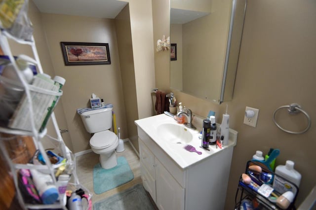 bathroom with toilet, vanity, and baseboards