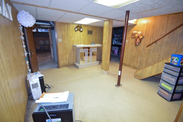 finished below grade area with visible vents, wood walls, and a paneled ceiling