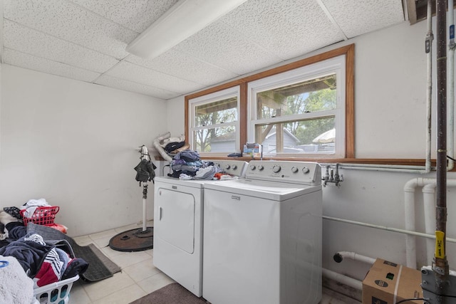 clothes washing area with plenty of natural light, washing machine and dryer, and light tile patterned floors