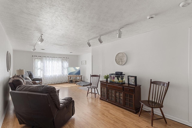 living room with light wood-type flooring, a textured ceiling, and rail lighting