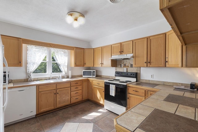 kitchen featuring sink, white appliances, tile counters, a textured ceiling, and tile patterned flooring