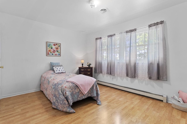 bedroom featuring a baseboard heating unit and light hardwood / wood-style floors