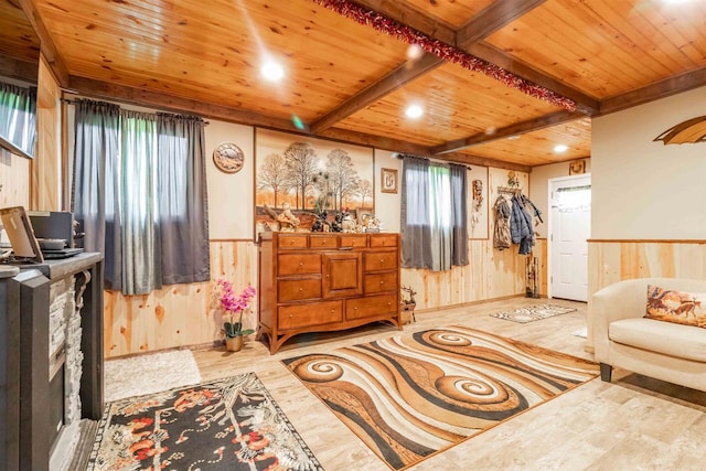 living area featuring wooden ceiling, wood walls, wainscoting, beamed ceiling, and plenty of natural light