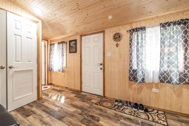 entrance foyer featuring lofted ceiling, visible vents, wood walls, wood finished floors, and wooden ceiling