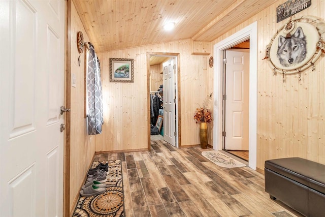 hallway with lofted ceiling, wooden ceiling, wood walls, and wood finished floors