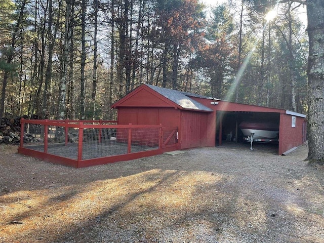 view of outdoor structure featuring a carport, an outbuilding, and driveway