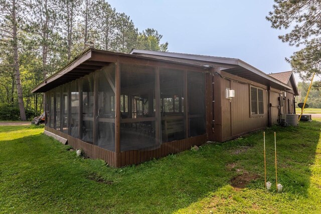 view of property exterior with central air condition unit, a yard, and a sunroom