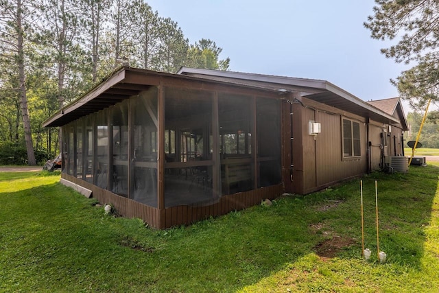 view of home's exterior featuring central air condition unit, a sunroom, and a yard