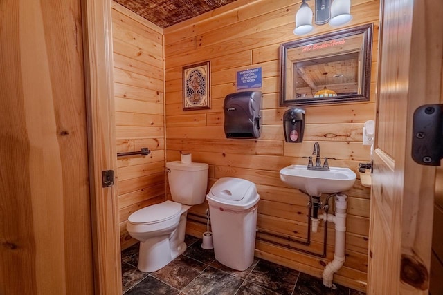 half bathroom featuring a sink, wooden walls, and toilet