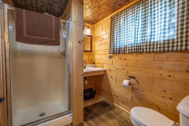 bathroom featuring a shower with shower door, wooden walls, toilet, and wood-type flooring