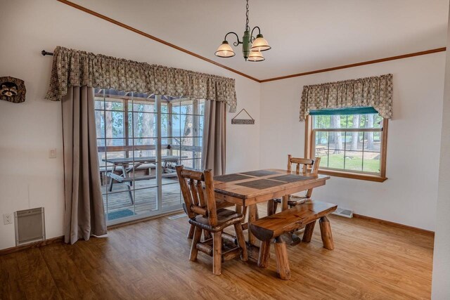 dining area featuring crown molding, wood-type flooring, and a chandelier