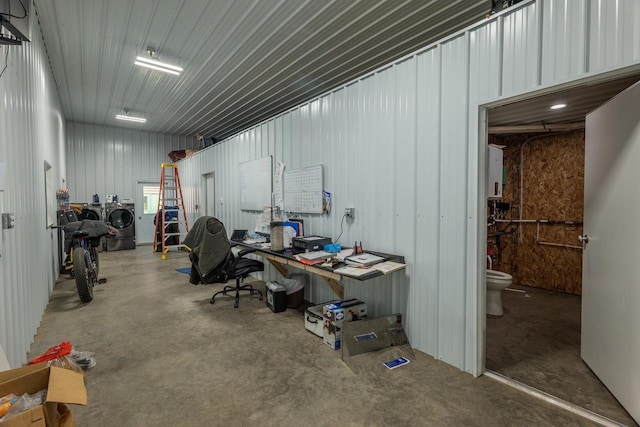 interior space with concrete flooring, independent washer and dryer, and metal wall