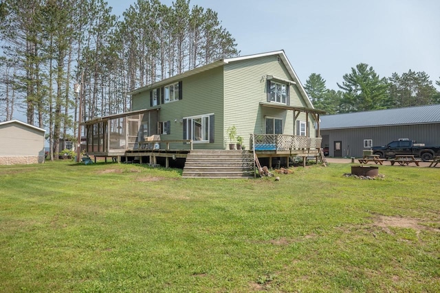 rear view of house with a lawn, a wooden deck, and a sunroom