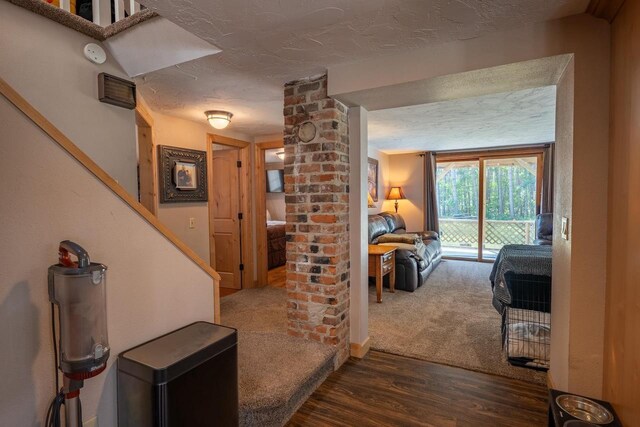 foyer featuring hardwood / wood-style flooring, decorative columns, brick wall, and a textured ceiling