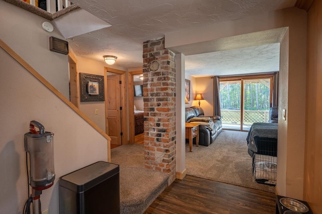 hall featuring stairs, dark wood finished floors, a textured ceiling, and decorative columns