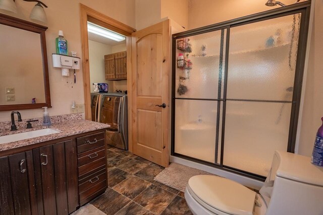 bathroom featuring vanity, washer and dryer, a shower with shower door, tile patterned floors, and toilet