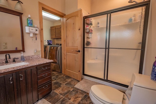 bathroom featuring toilet, a stall shower, vanity, and independent washer and dryer