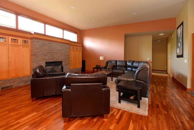 living room with a stone fireplace and dark hardwood / wood-style flooring