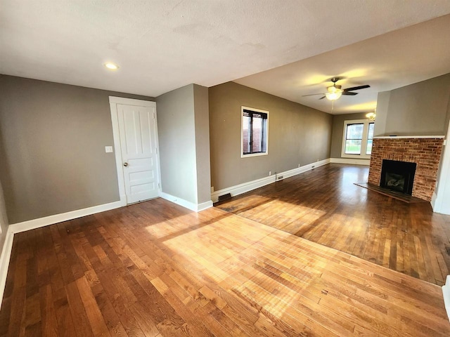 unfurnished living room with a brick fireplace, baseboards, and wood-type flooring