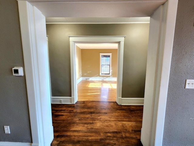 hallway with baseboards, wood finished floors, and crown molding