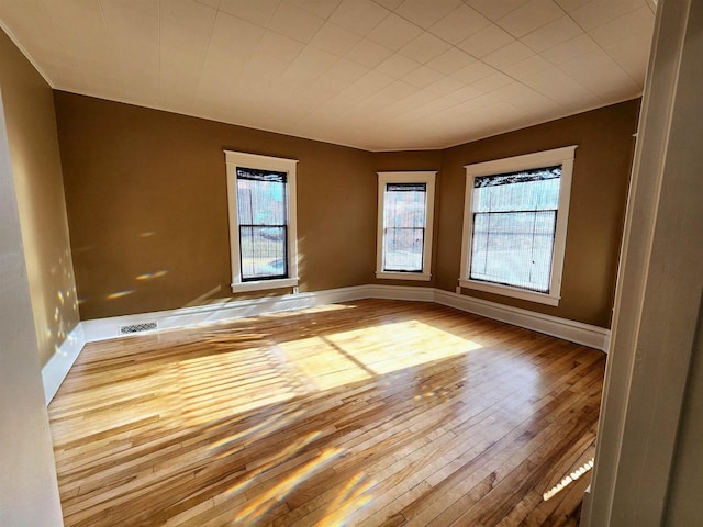 spare room featuring visible vents, baseboards, and hardwood / wood-style flooring